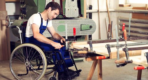 man in wheelchair working in wood shop
