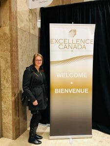 Staff member in front of Excellence Canada sign