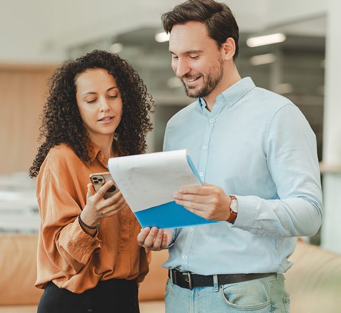 Man and woman standing while looking at a tablet.