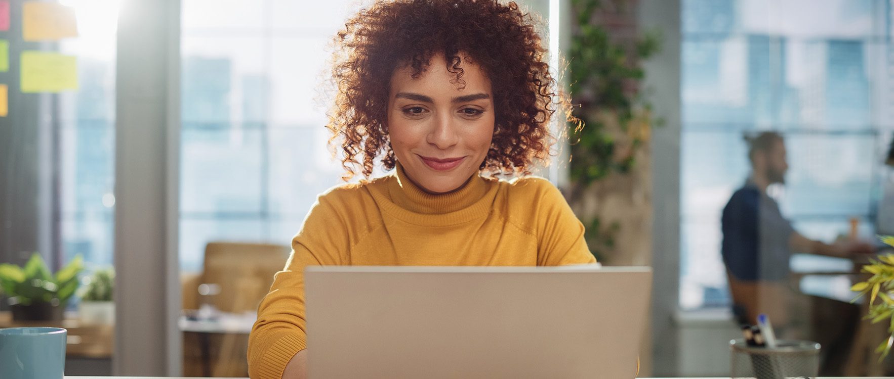 Woman sitting at desk, working on a laptop.