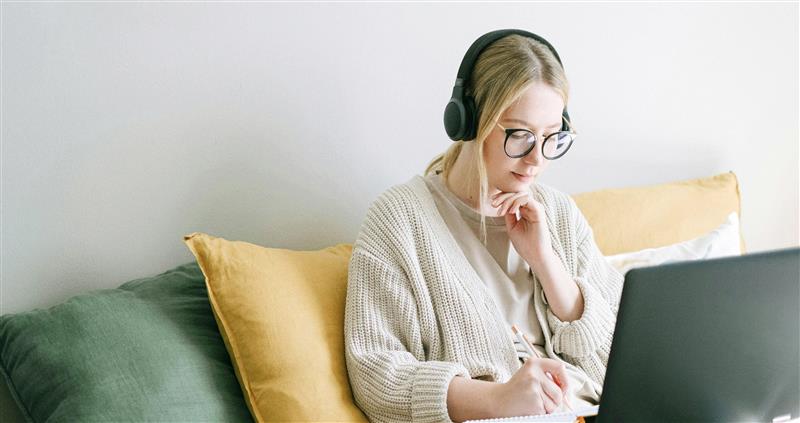 image 15 Woman sitting on couch with headphones and a computer.